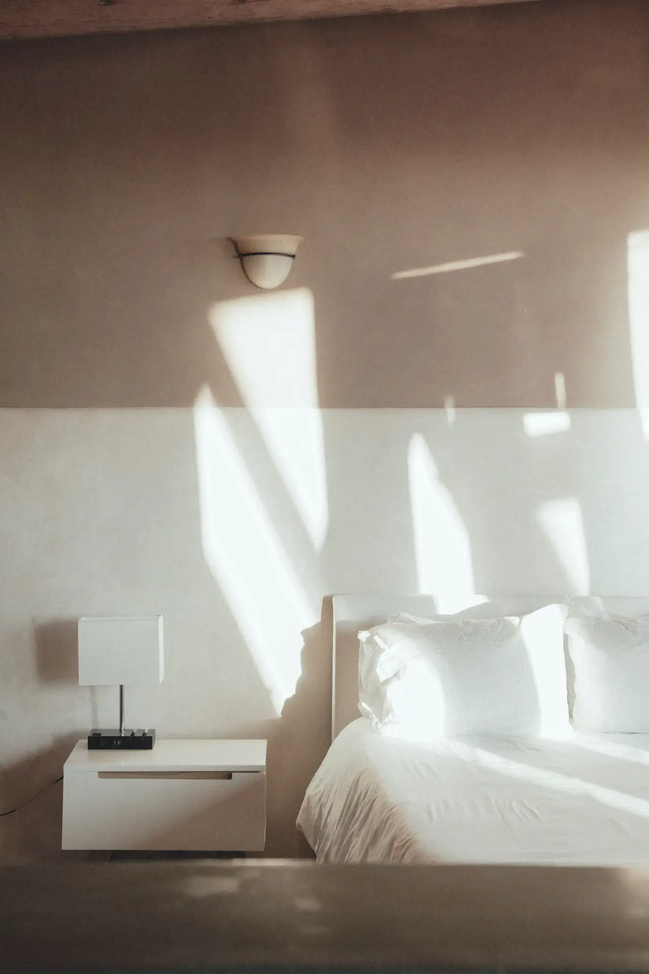 Mur rose, soleil sur le lit blanc